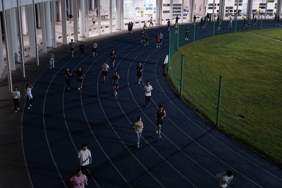 Grupa ljudi trči na vanjskom stadionu u večernjim satima